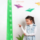 little gril pointing at a dino height chart wall sticker